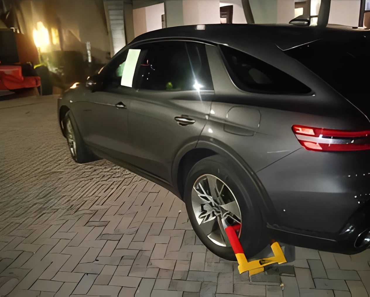 Dark SUV immobilized with yellow wheel clamp